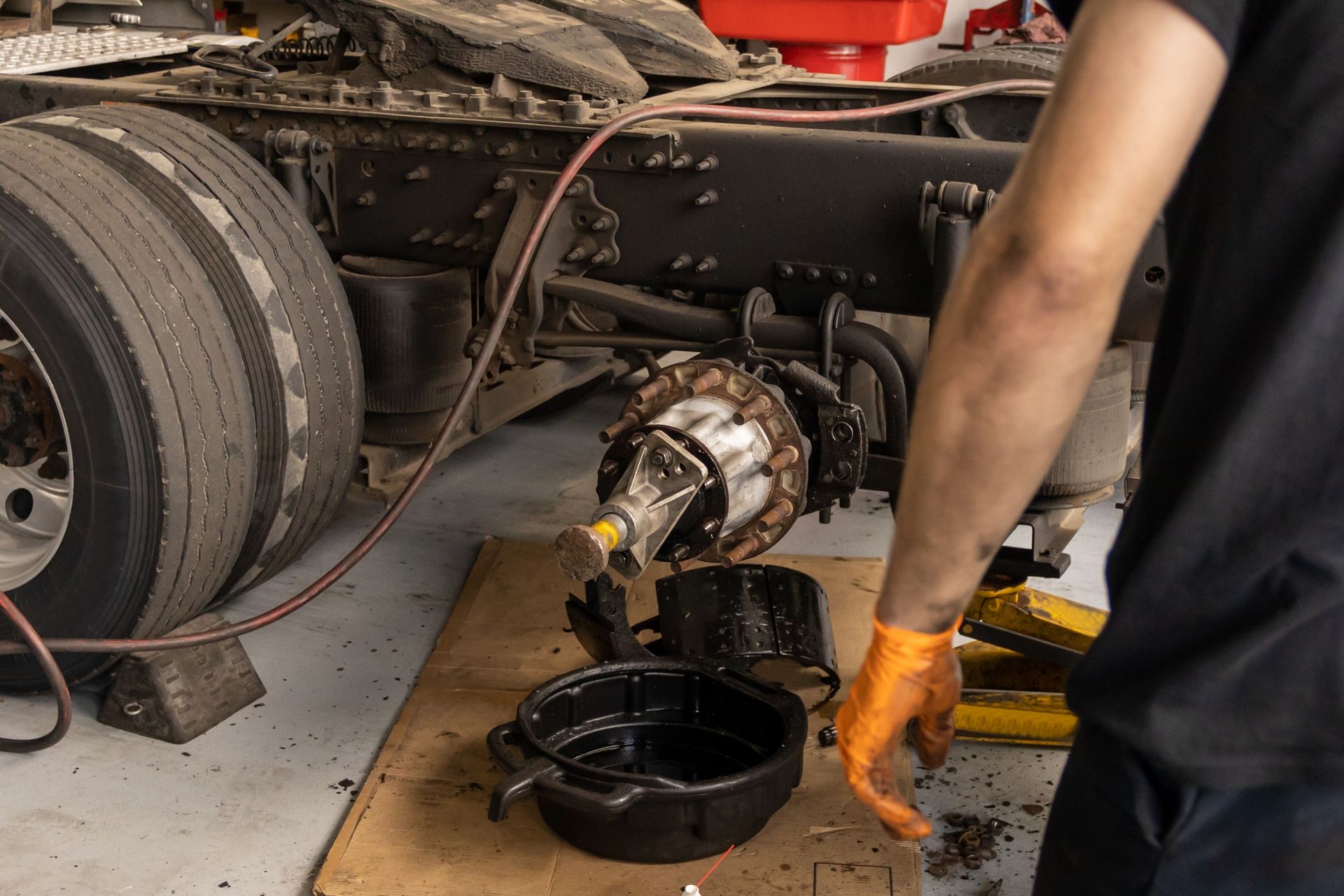 A man is draining oil out of a truck in a garage.