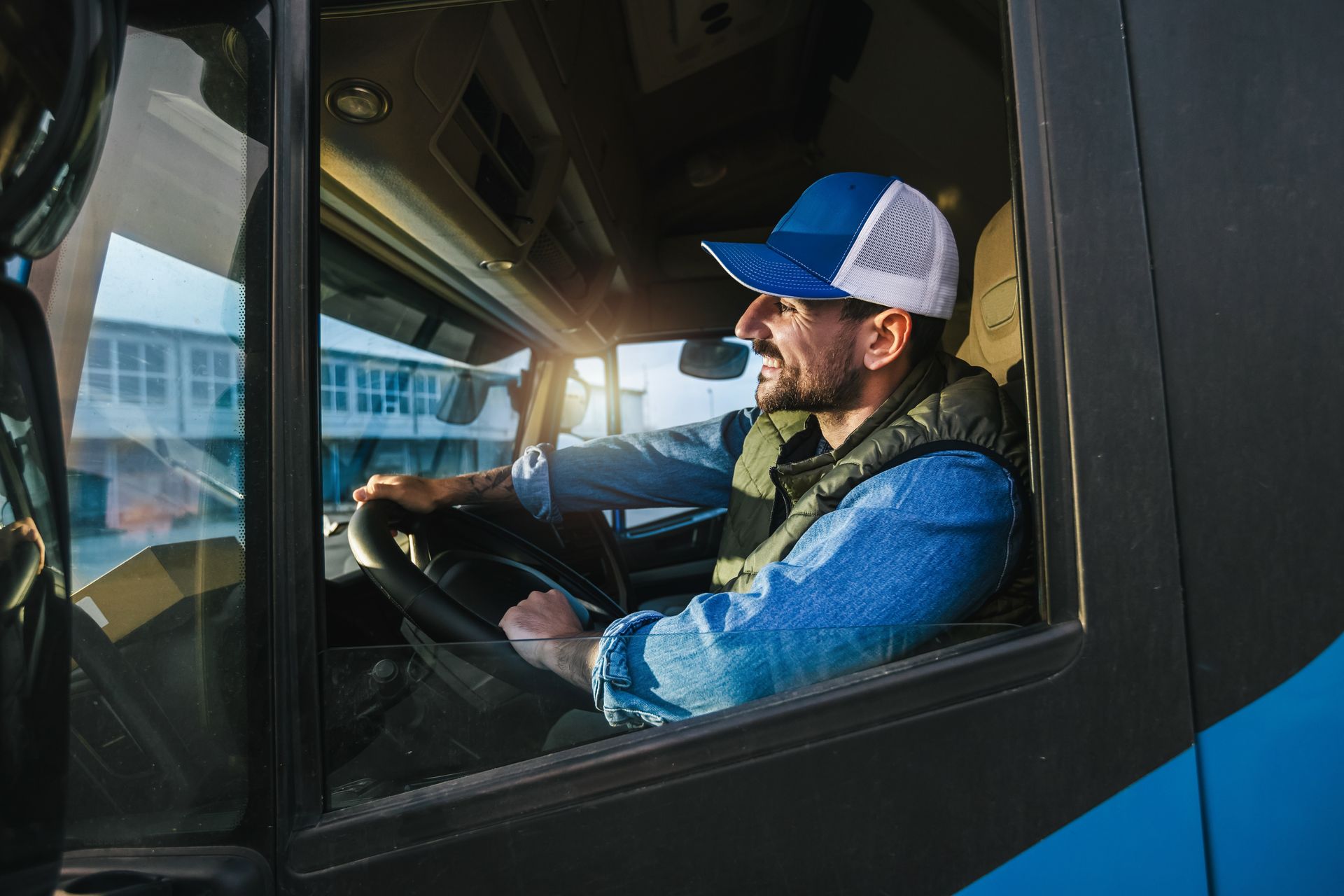 A man is driving a truck and looking out the window.