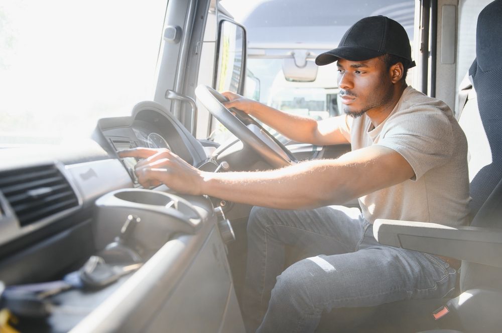 A man is sitting in the driver 's seat of a truck.