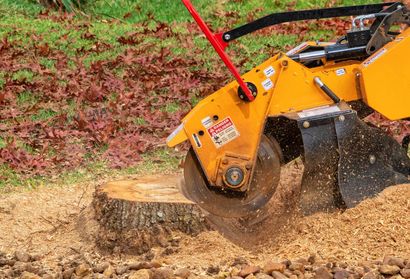 A stump grinder is cutting a tree stump in the ground