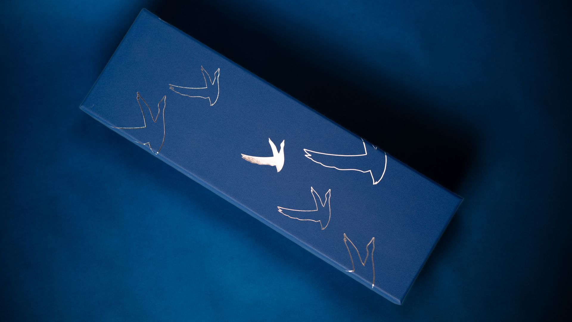 navy blue bottle box featuring silver foil logo.