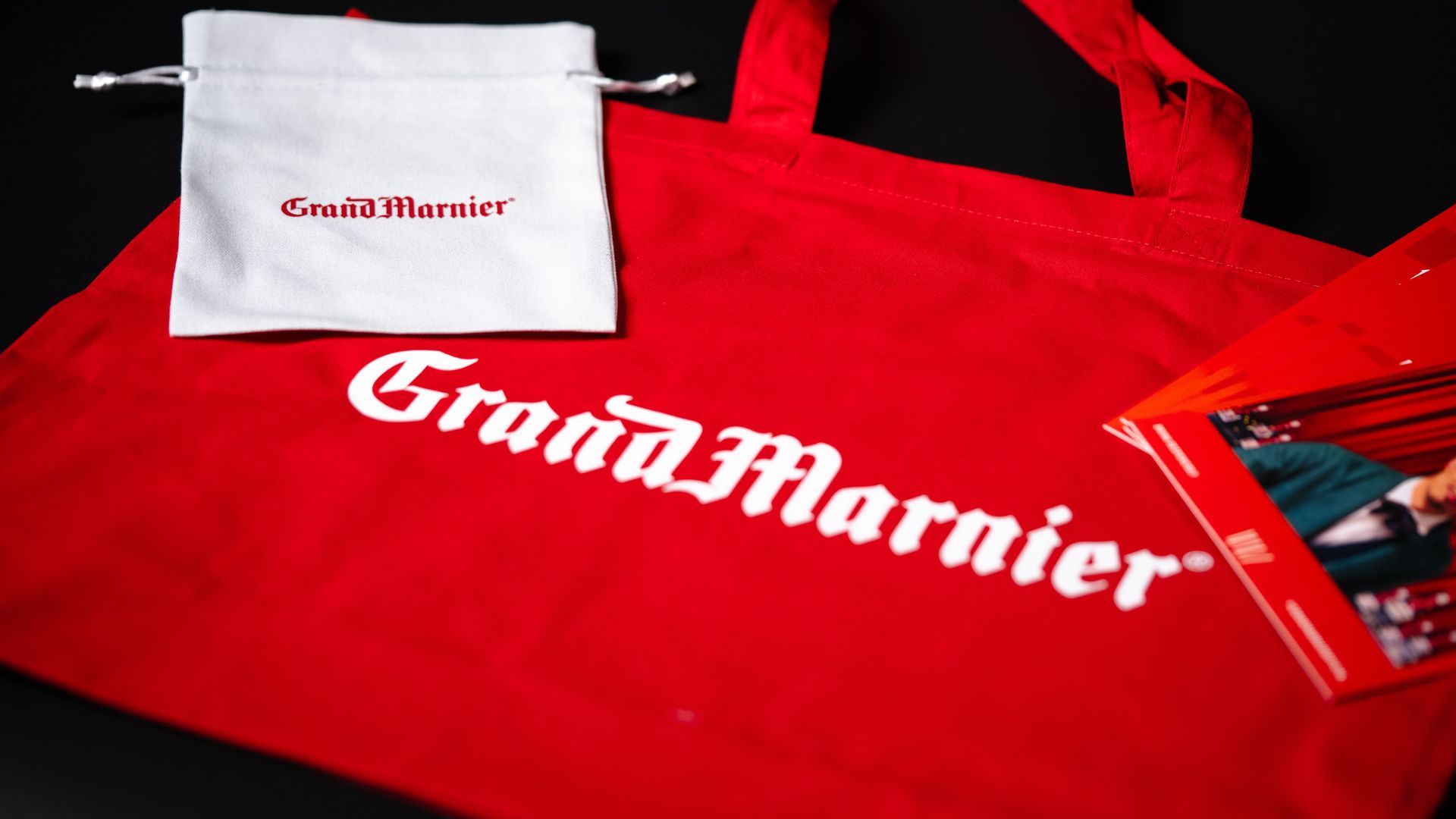 Bright red tote bag featuring a custom printed logo and text.
