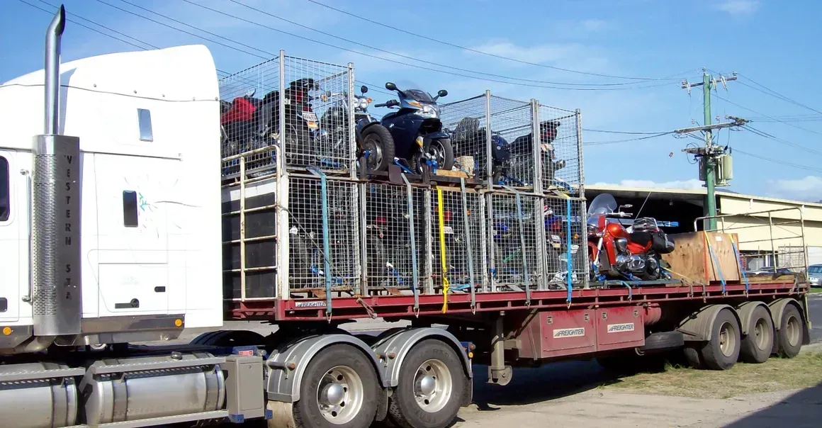 A Semi Truck Is Loaded With Motorcycles On A Flatbed Trailer — Motorcycle Transporters In Manunda, QLD