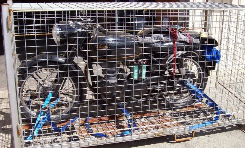 A Motorcycle Is Sitting In A Wire Cage — Motorcycle Transporters In Manunda, QLD
