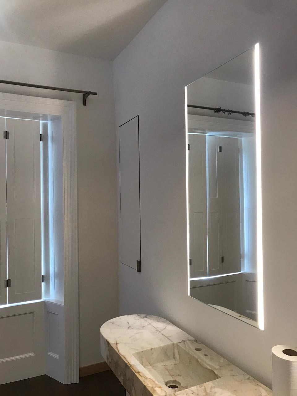 picture of unfinished bathroom with white marmorino walls and a mirror with led lights
