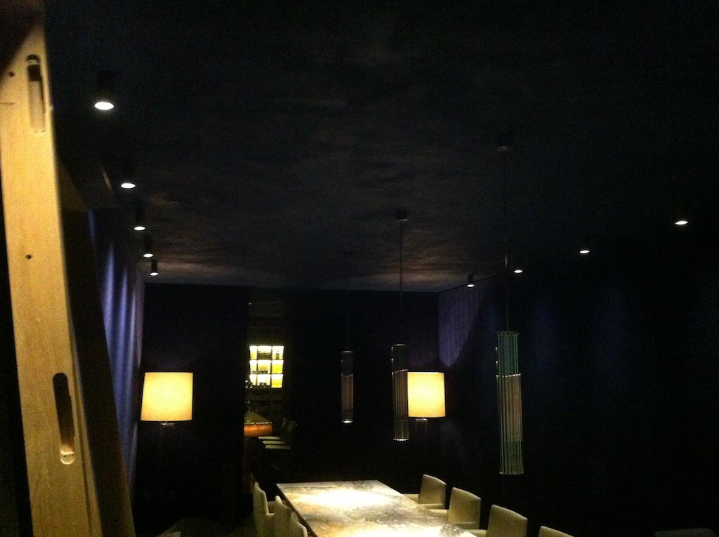 picture of a dark dining room with two lamps and deep violet suede walls