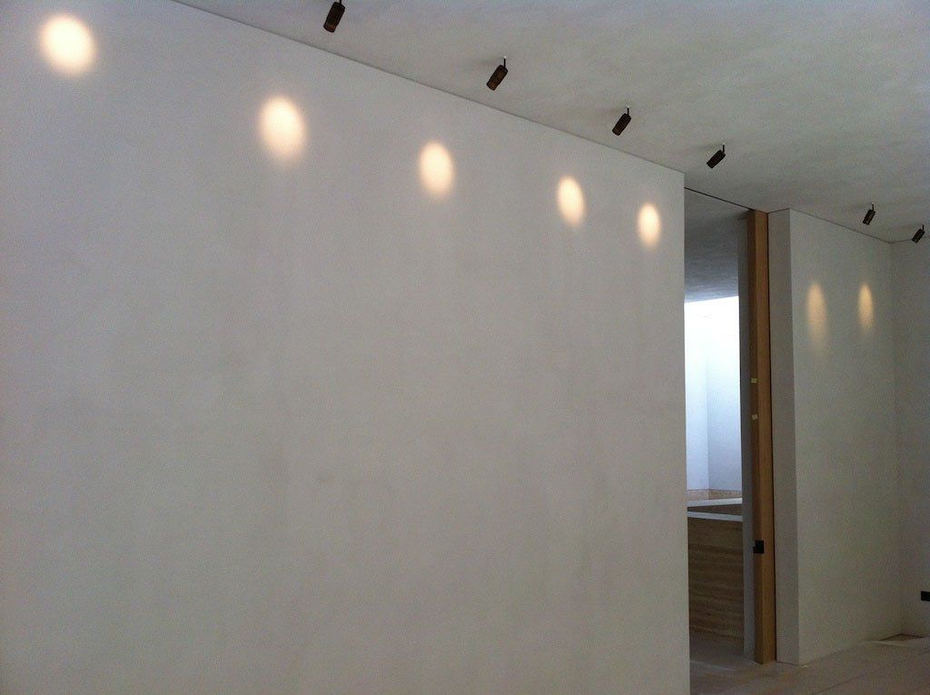 detail of a straight wall finished with white suede product and some wall lights