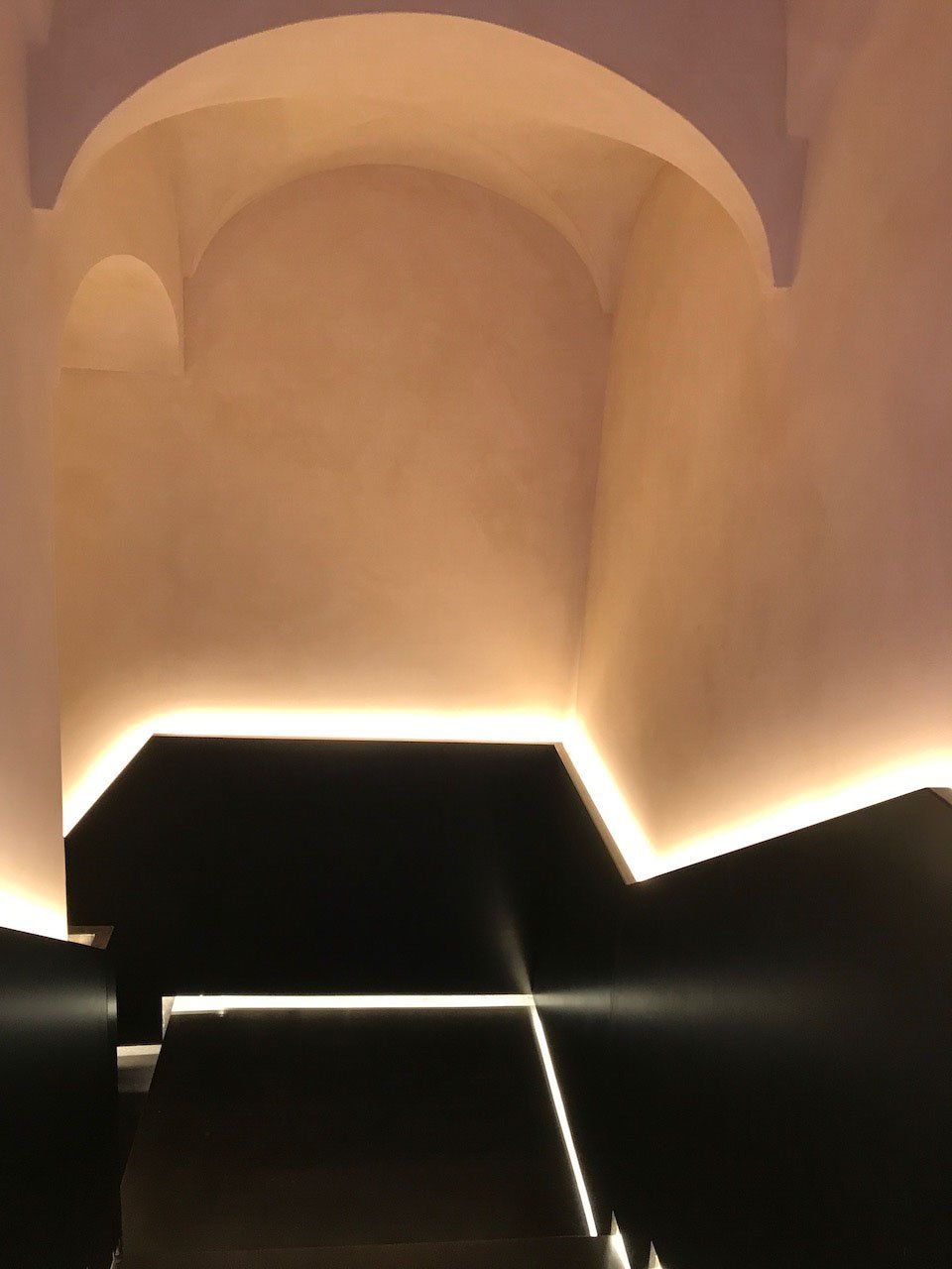 picture of stairs with sand suede walls with glazing and led light along the handrail