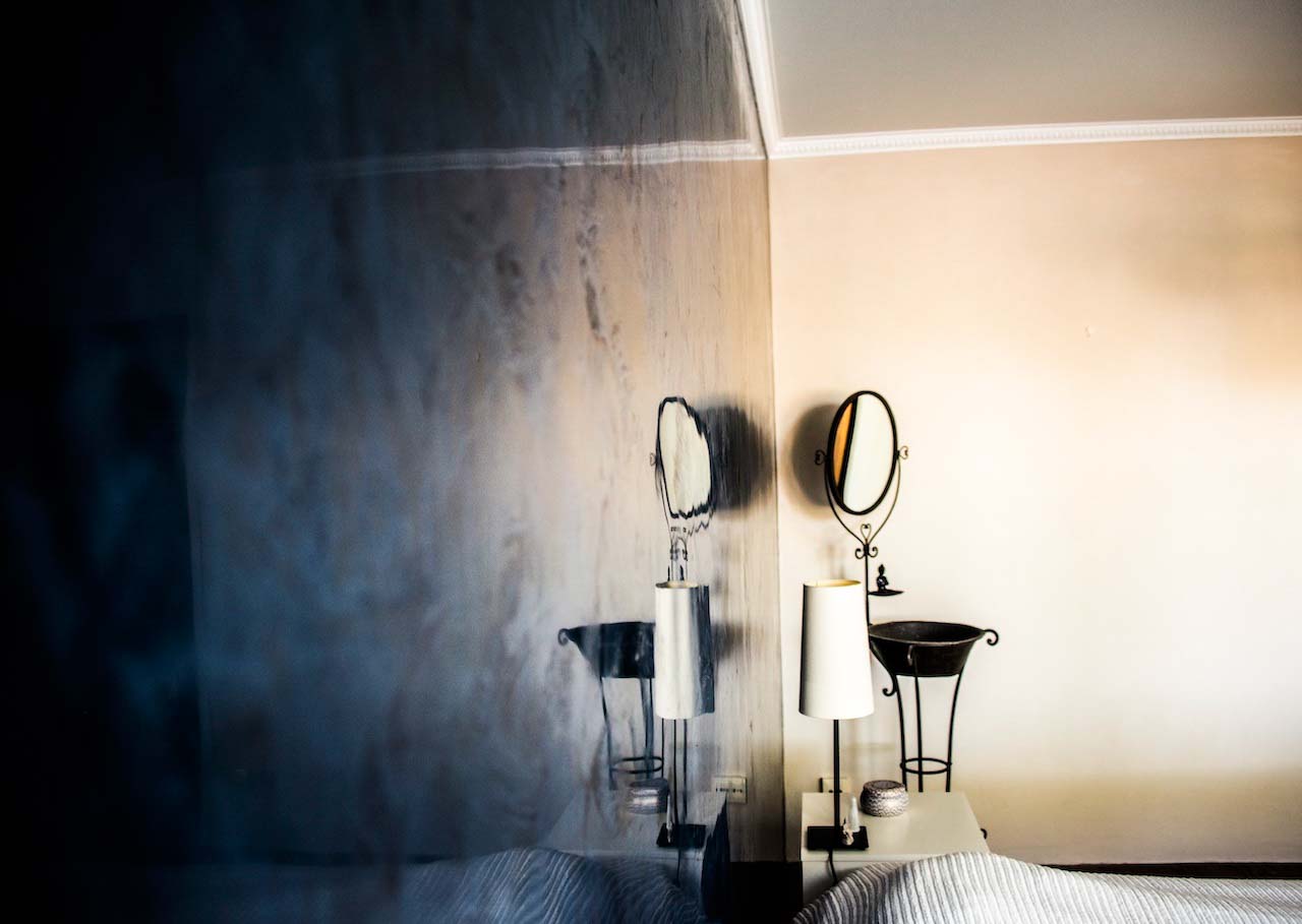 picture of a bedroom polished wall in deep blue tadelakt product with a lamp and a mirror