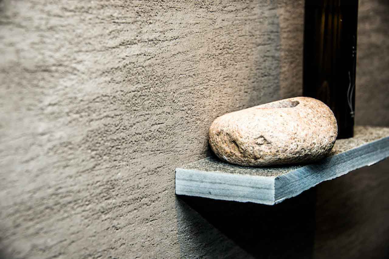 detail of a sauna wall customized with beige tadelakt product and a stone
