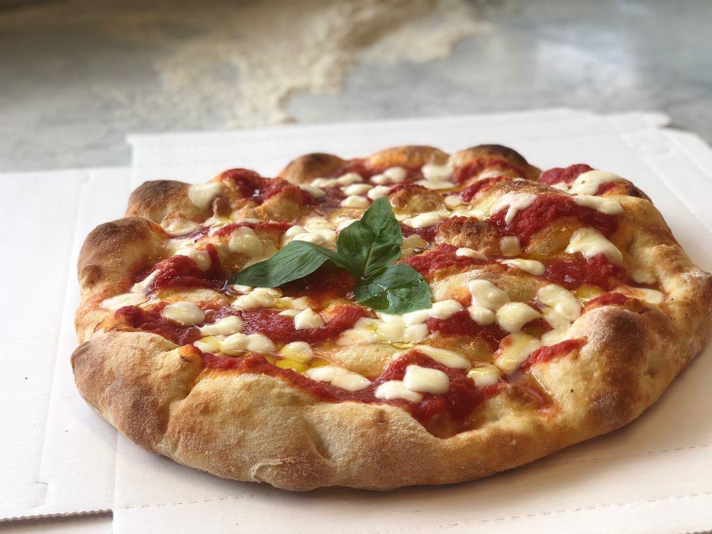 Una pizza con salsa di pomodoro e formaggio è appoggiata su una scatola di cartone.