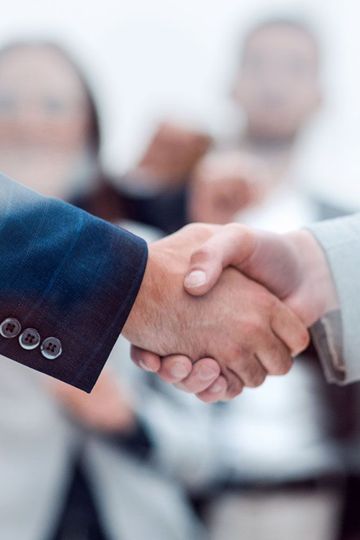 Two people in suits shaking hands; business agreement or deal.