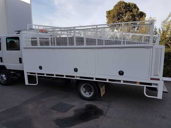 A white truck with a cage on the back is parked in a parking lot.