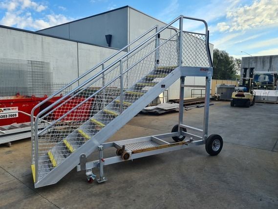 A metal staircase with wheels is sitting in front of a building.