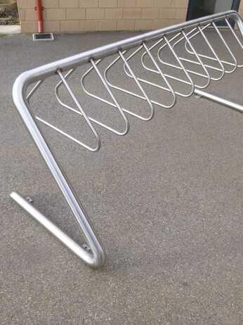 A bicycle rack is sitting on the ground in a parking lot.