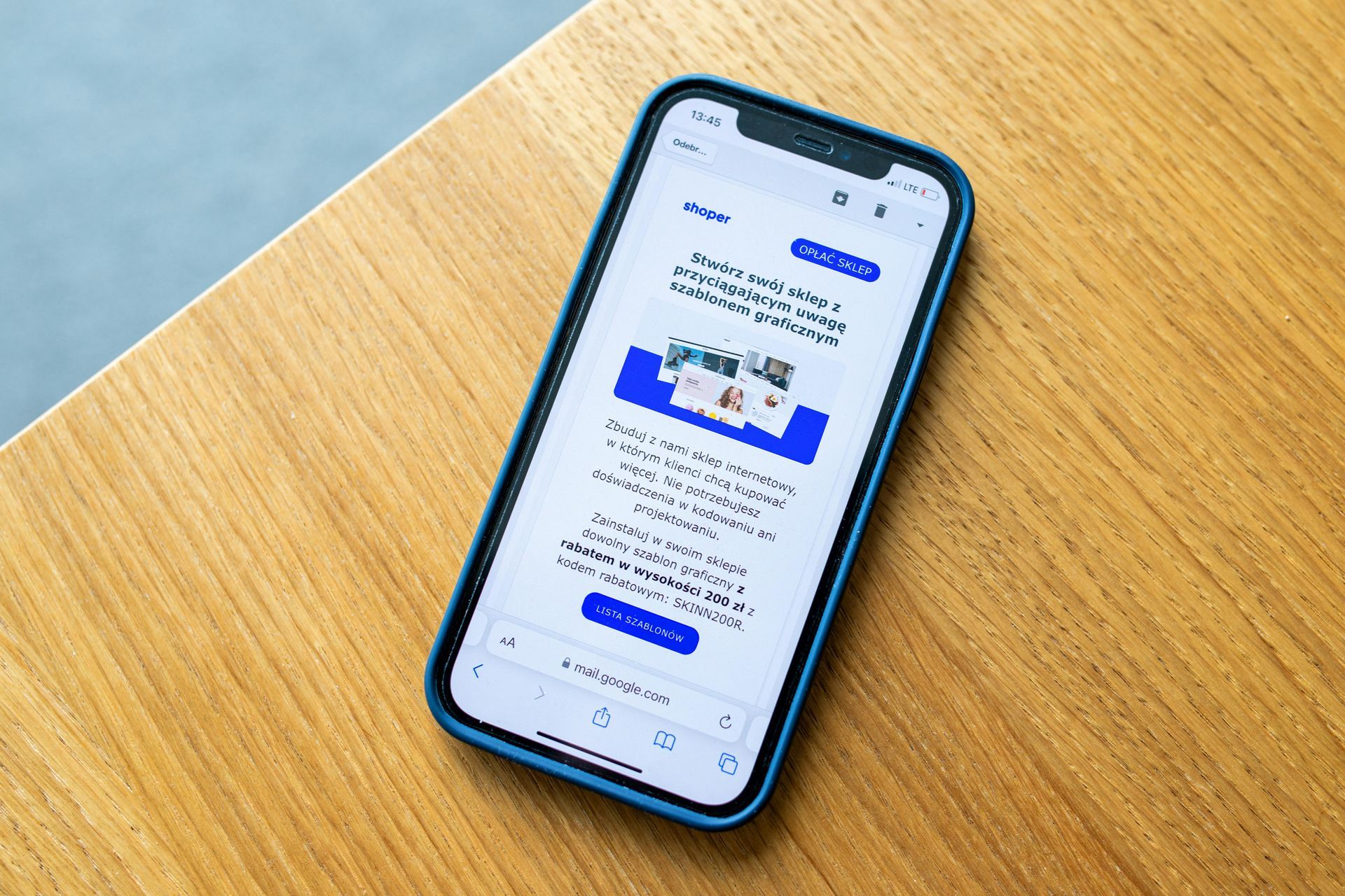 Smartphone on a wooden table displaying a webpage with blue and white elements.