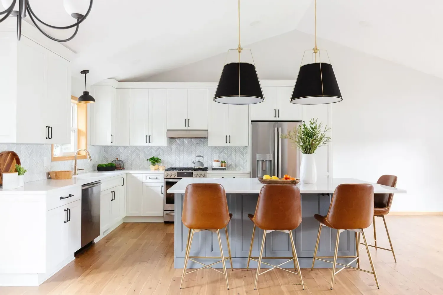 A kitchen with white cabinets , stainless steel appliances , and a large island.