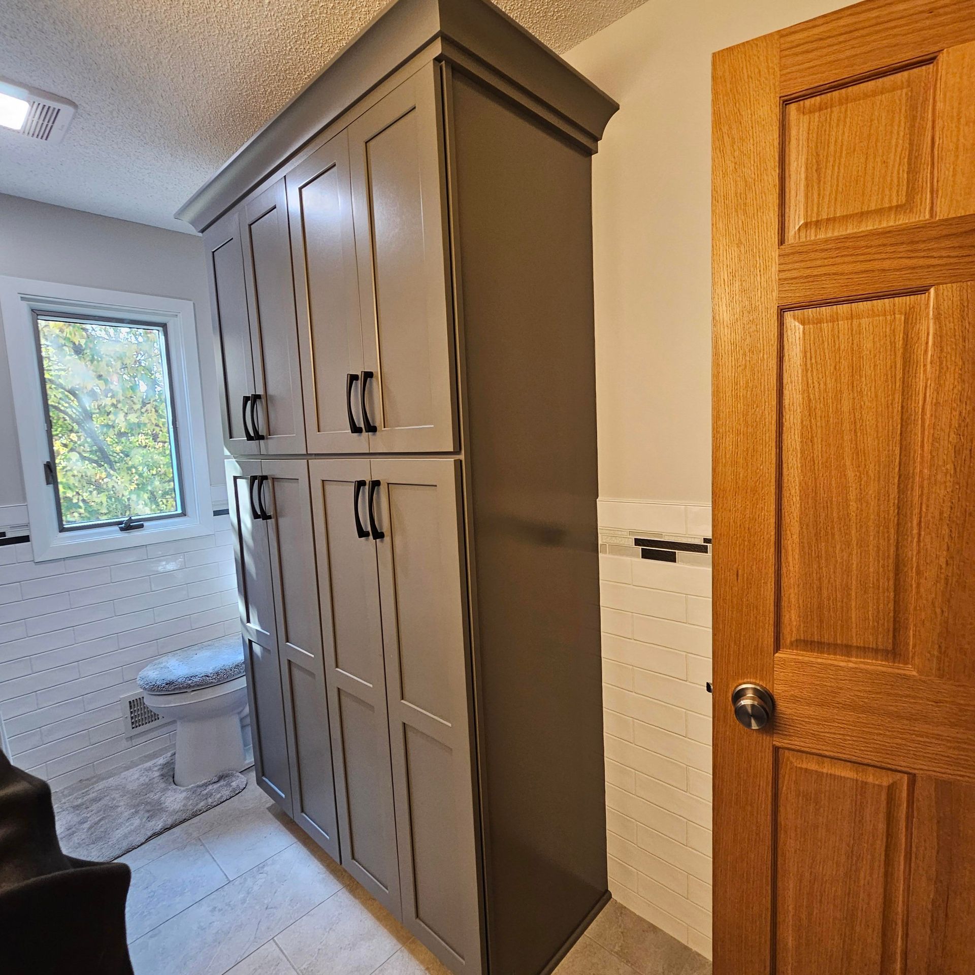 A bathroom with gray cabinets and a wooden door