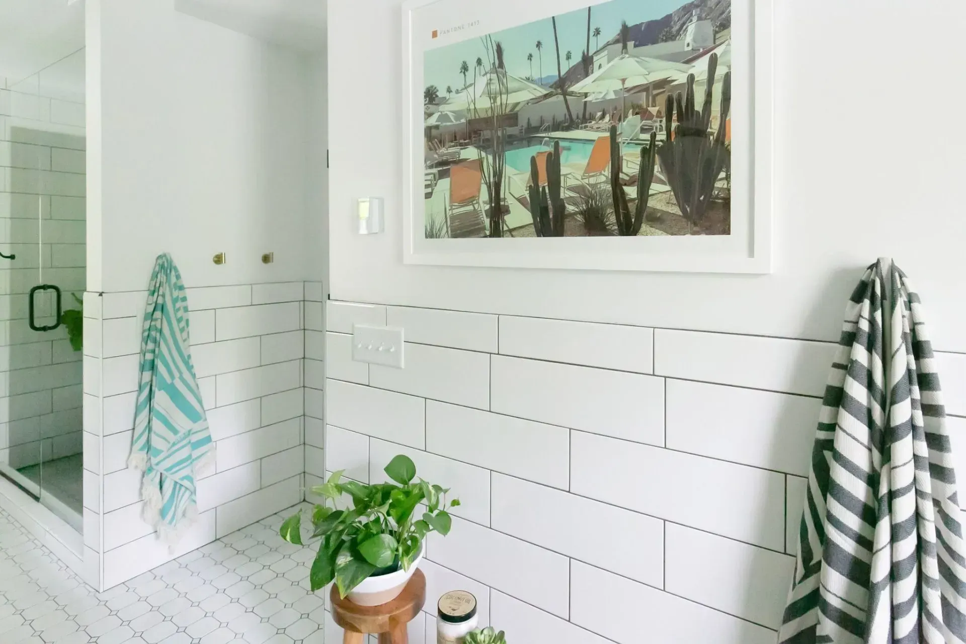 A bathroom with white tiles and a picture on the wall.