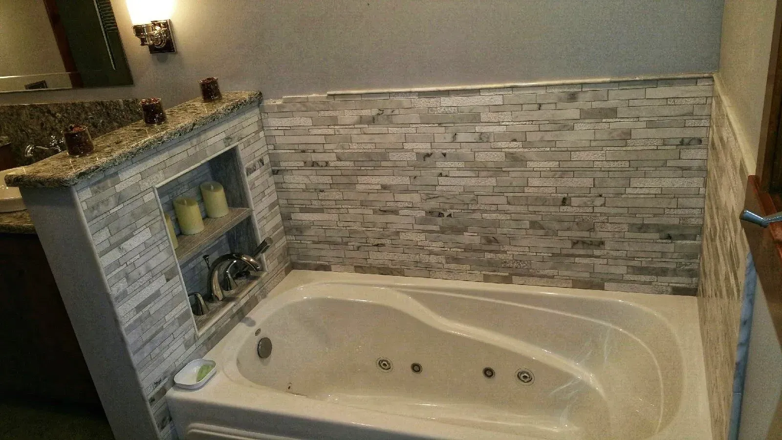 A bathroom with a jacuzzi tub and a stone wall.
