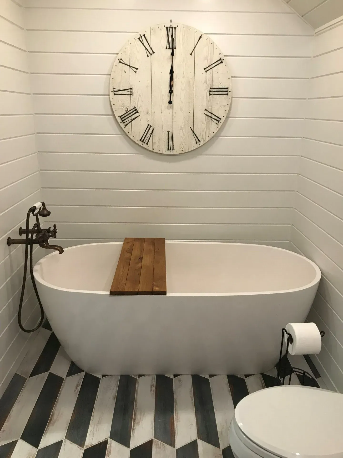 A bathroom with a bathtub , toilet , and clock on the wall.