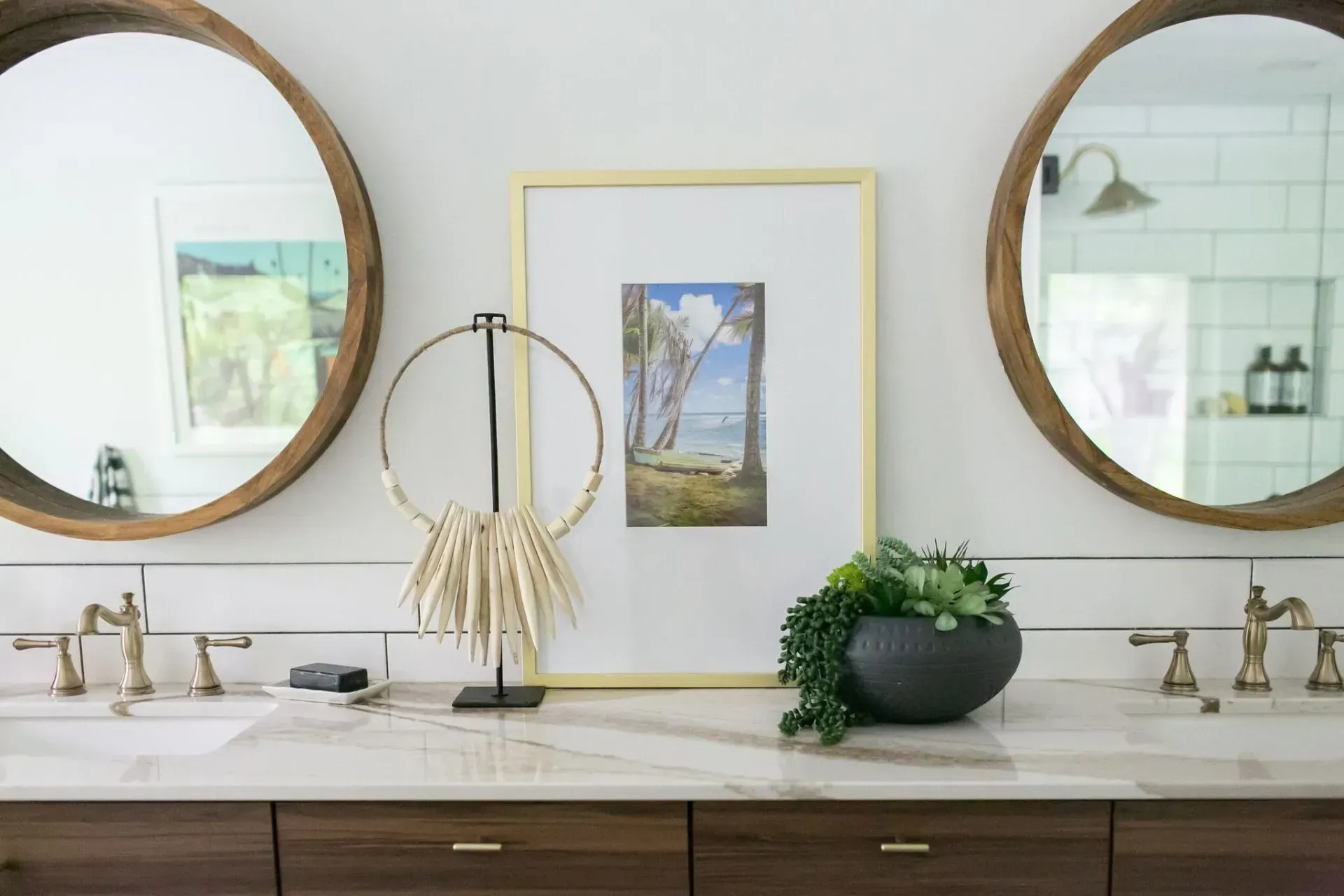A bathroom with two sinks , two mirrors and a picture on the counter.