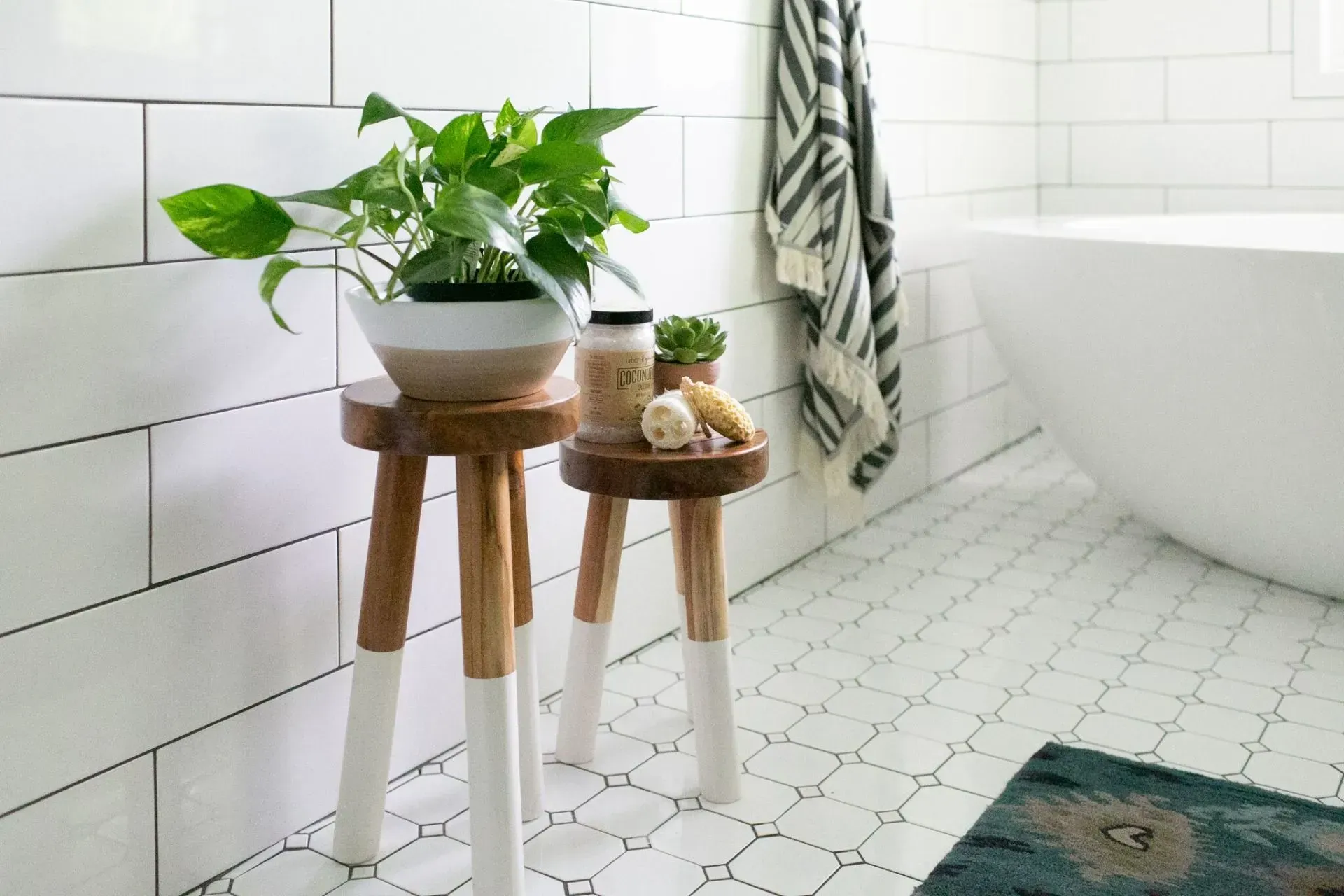 Two wooden stools in a bathroom next to a bathtub.