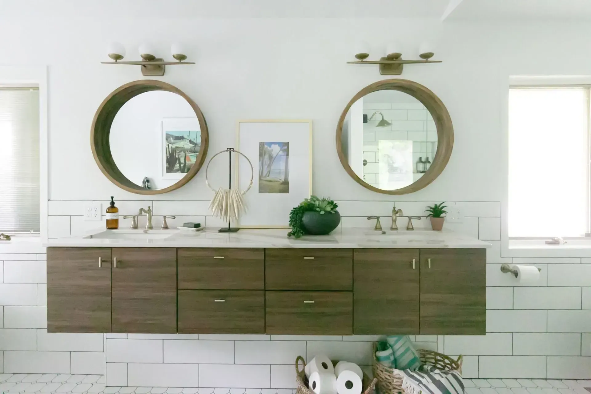 A bathroom with two sinks , two mirrors and a basket of toilet paper.