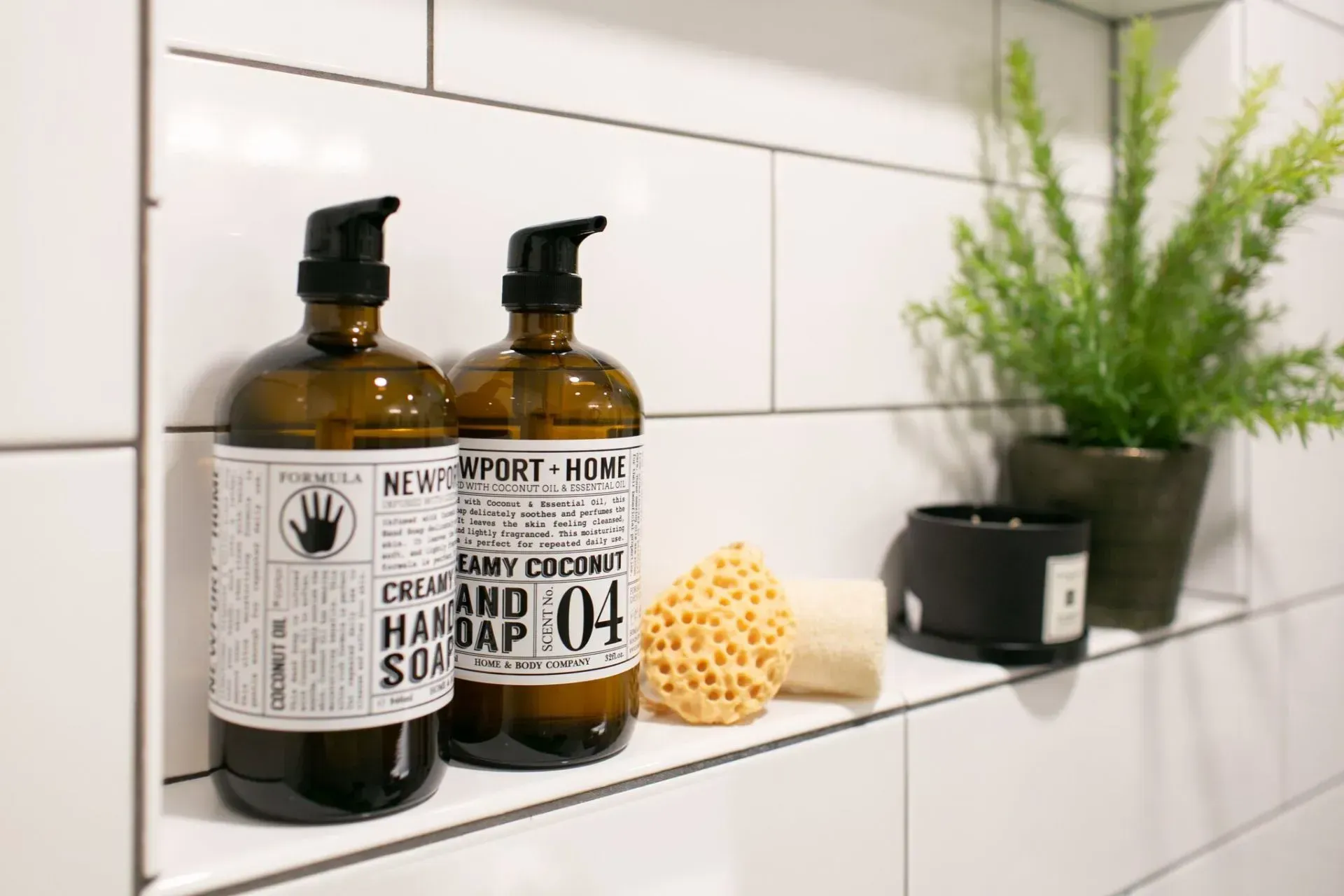 Two bottles of hand soap are sitting on a shelf in a bathroom.
