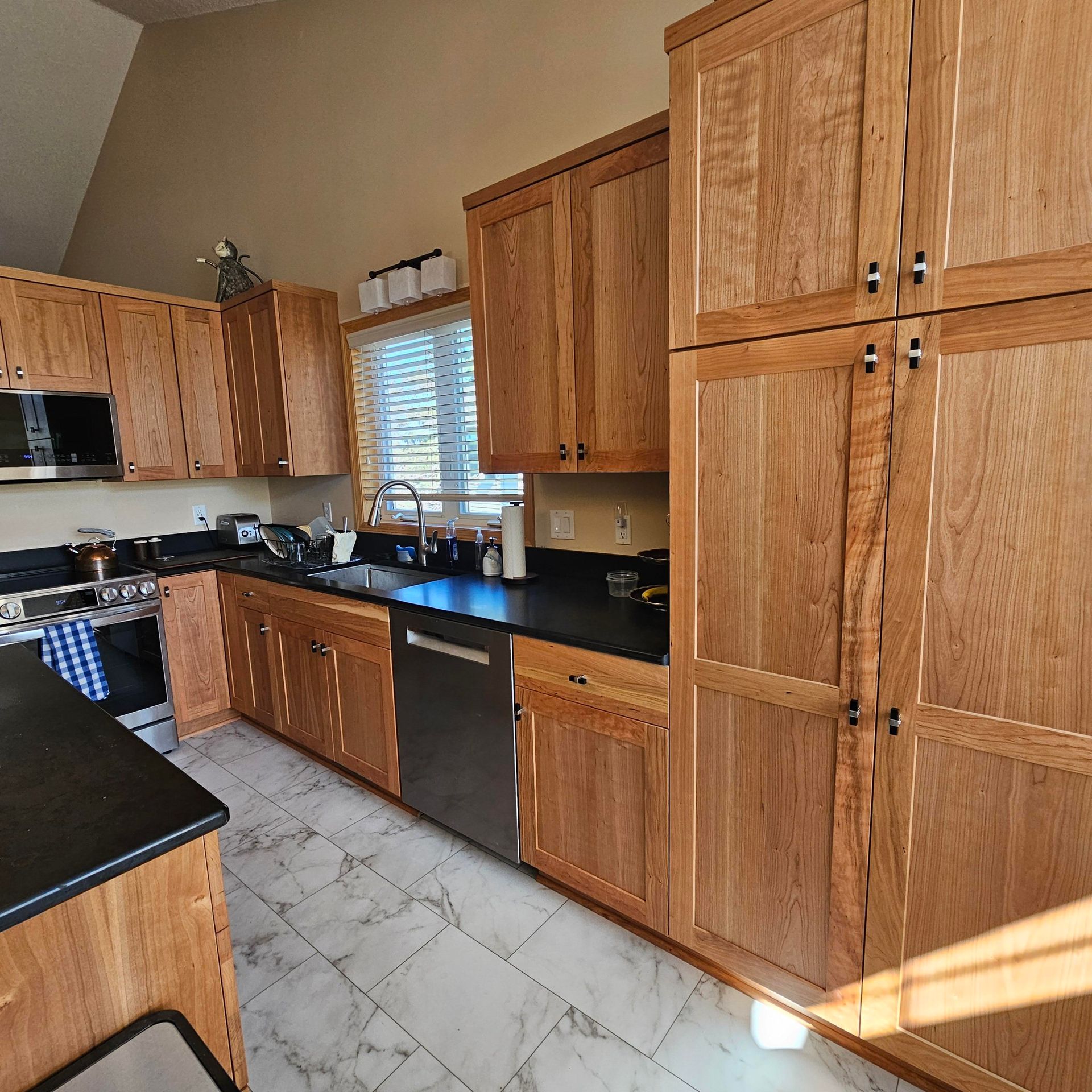 A kitchen with wooden cabinets and black counter tops
