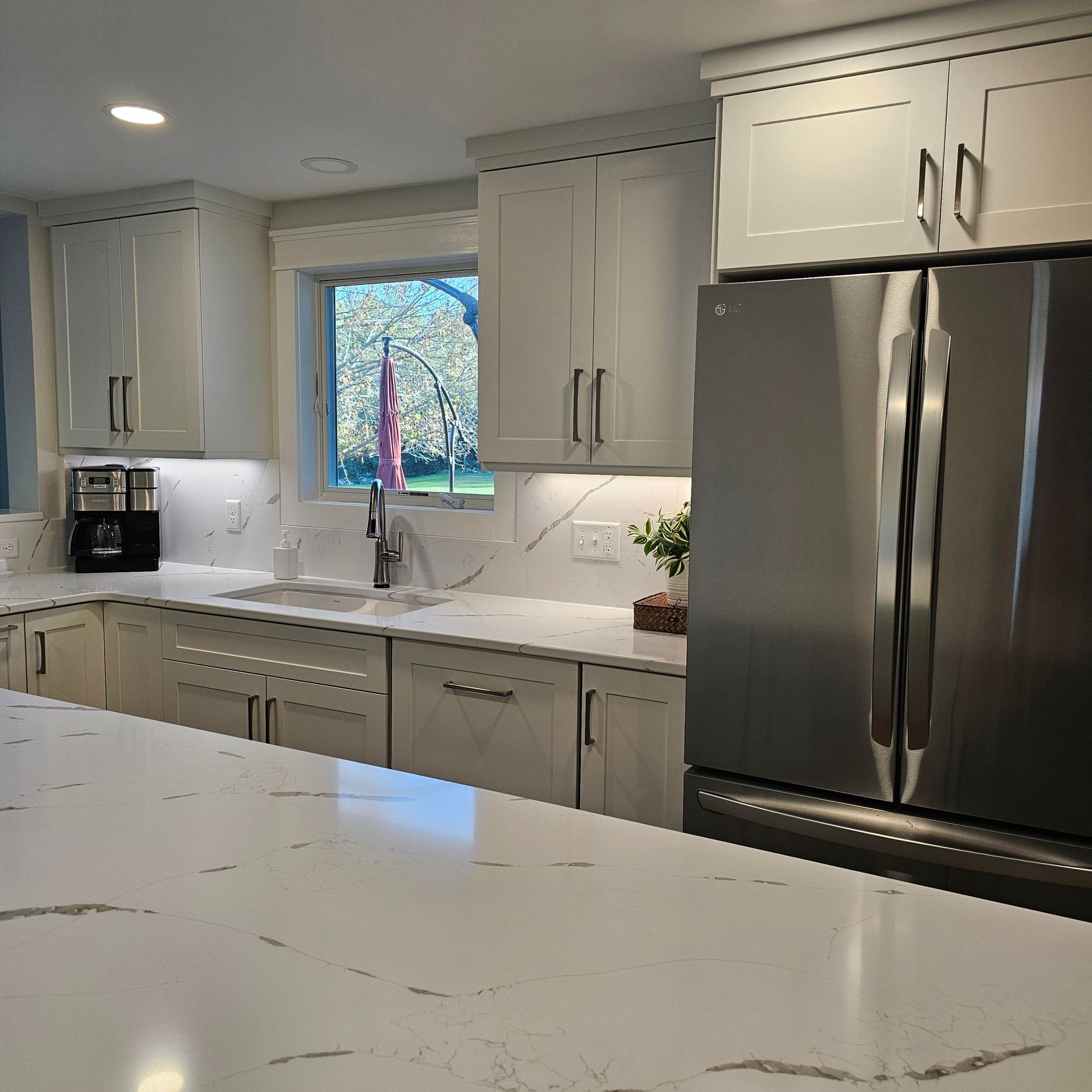 A kitchen with white cabinets and a stainless steel refrigerator