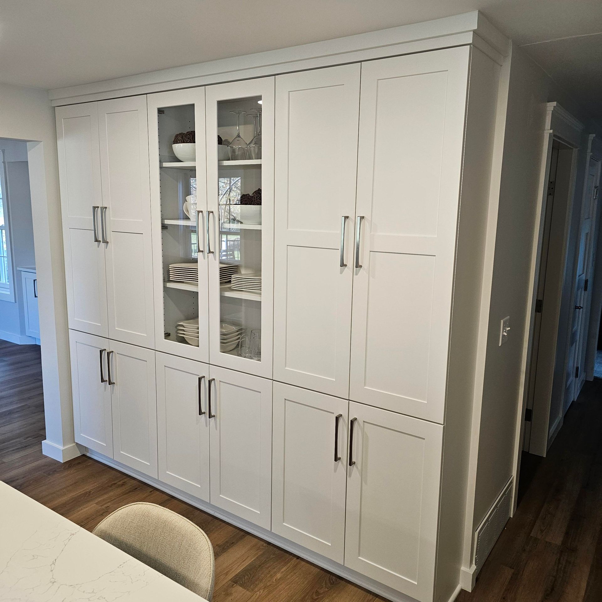 A kitchen with a lot of white cabinets and glass doors.