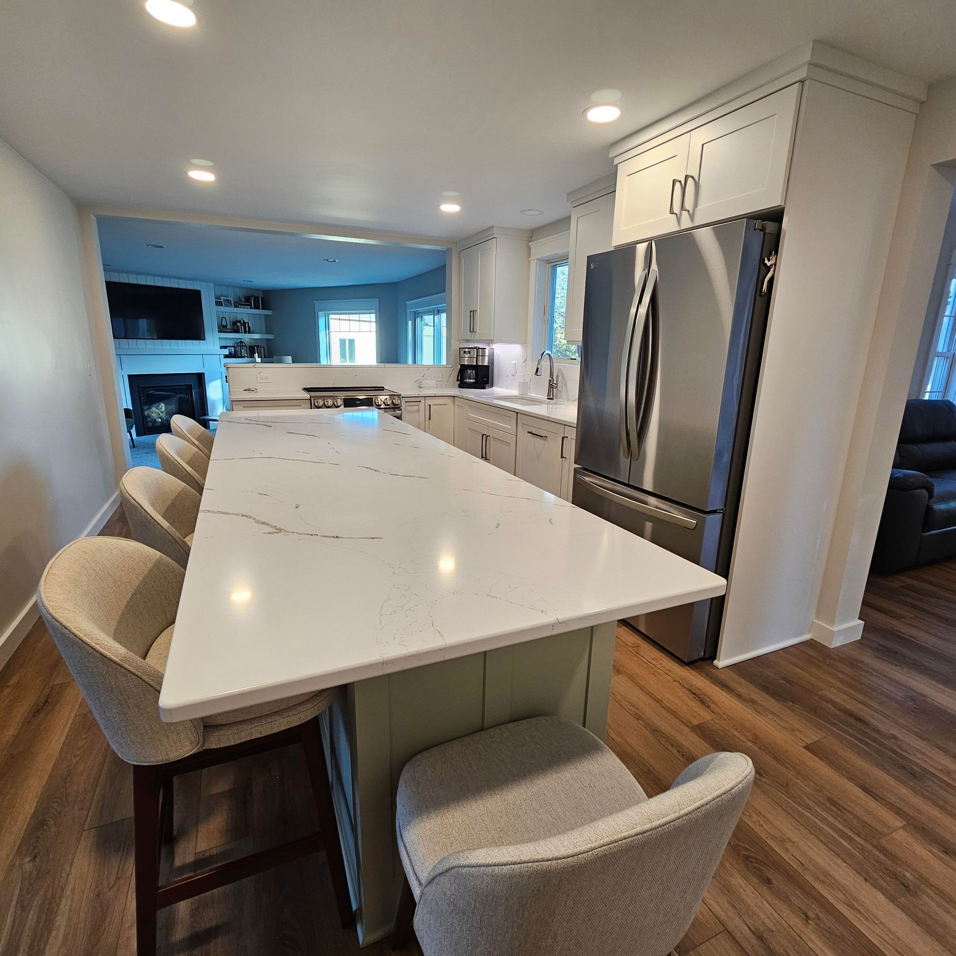 A kitchen with a long white counter top and stainless steel appliances