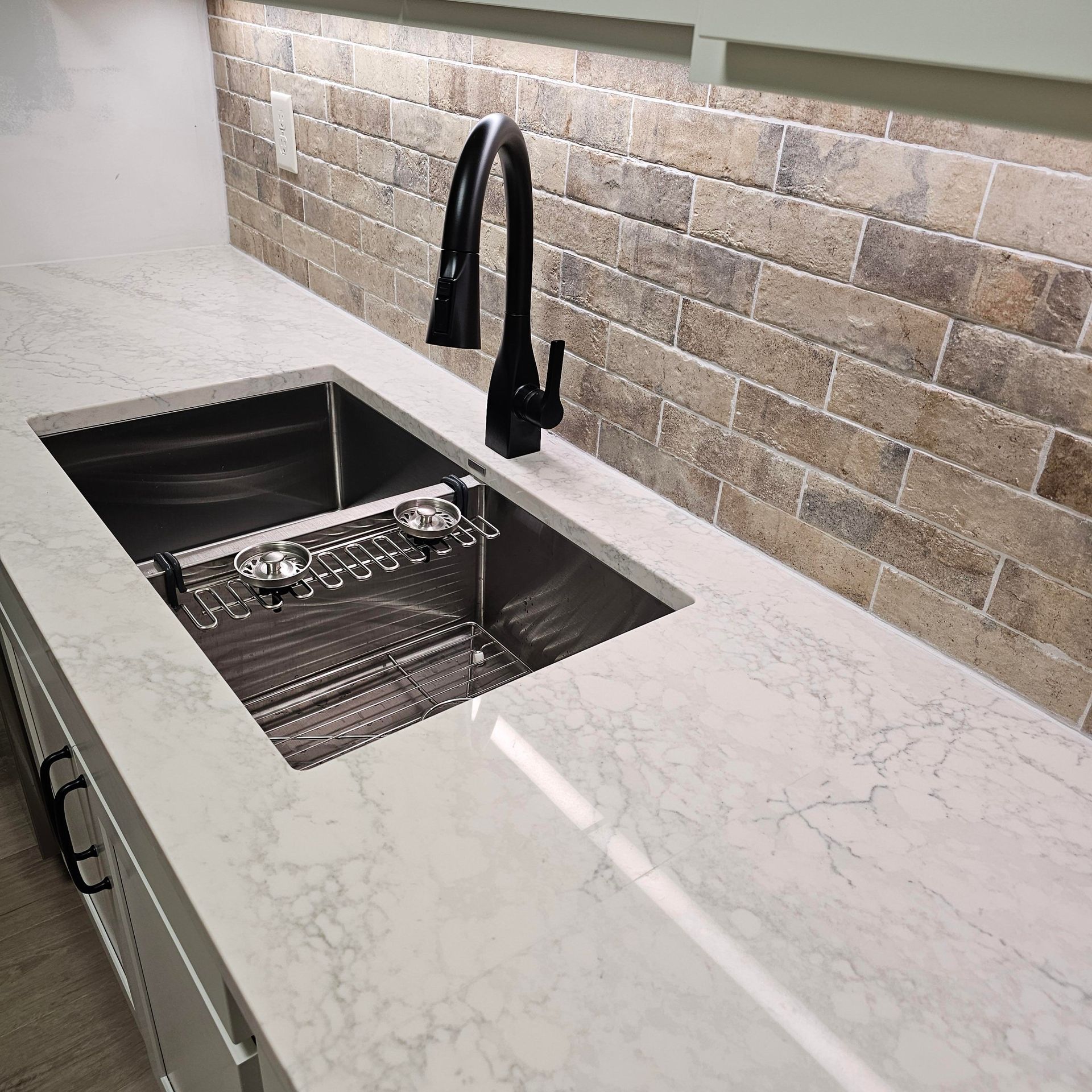 A kitchen with a stainless steel sink and a black faucet