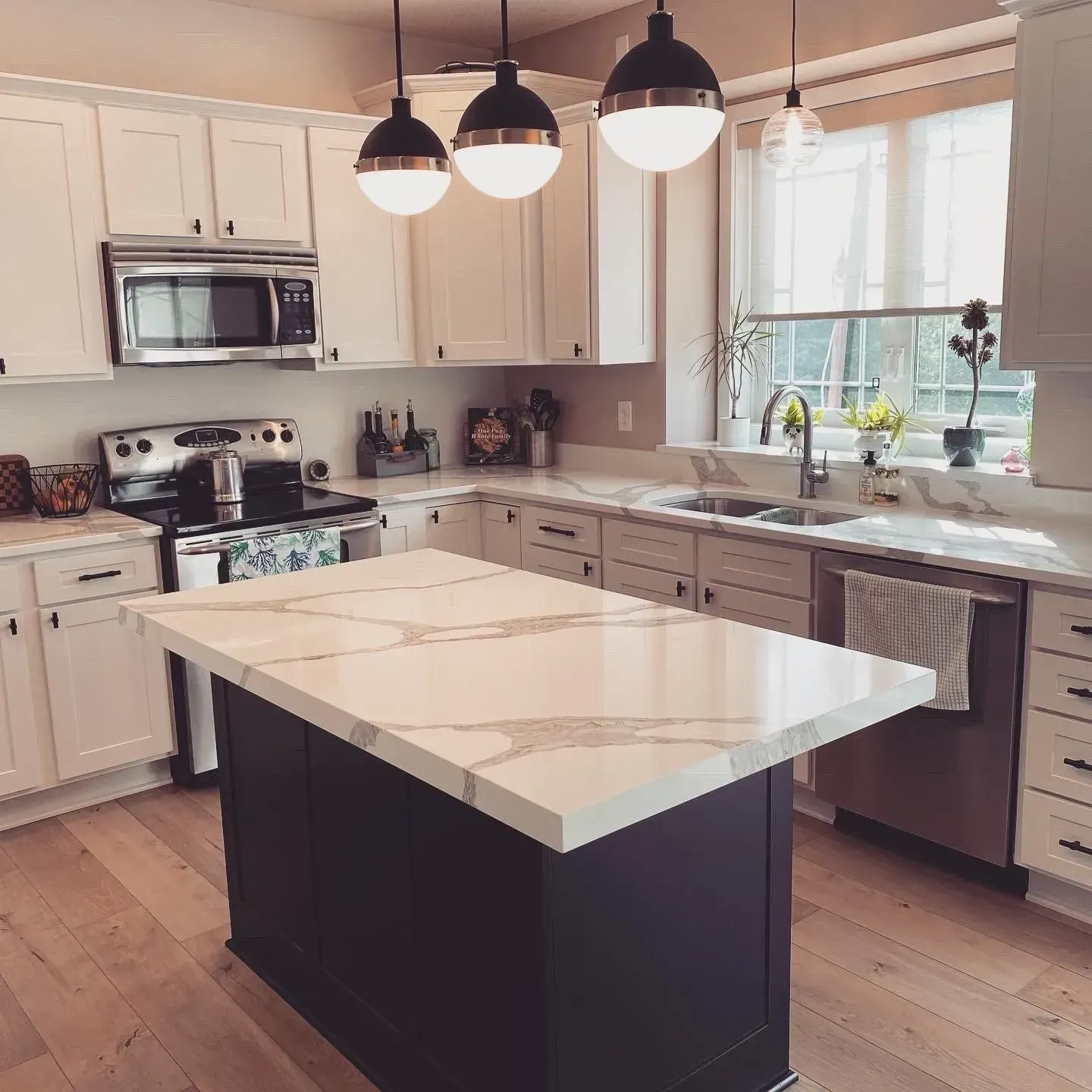 A kitchen with white cabinets and a large island in the middle