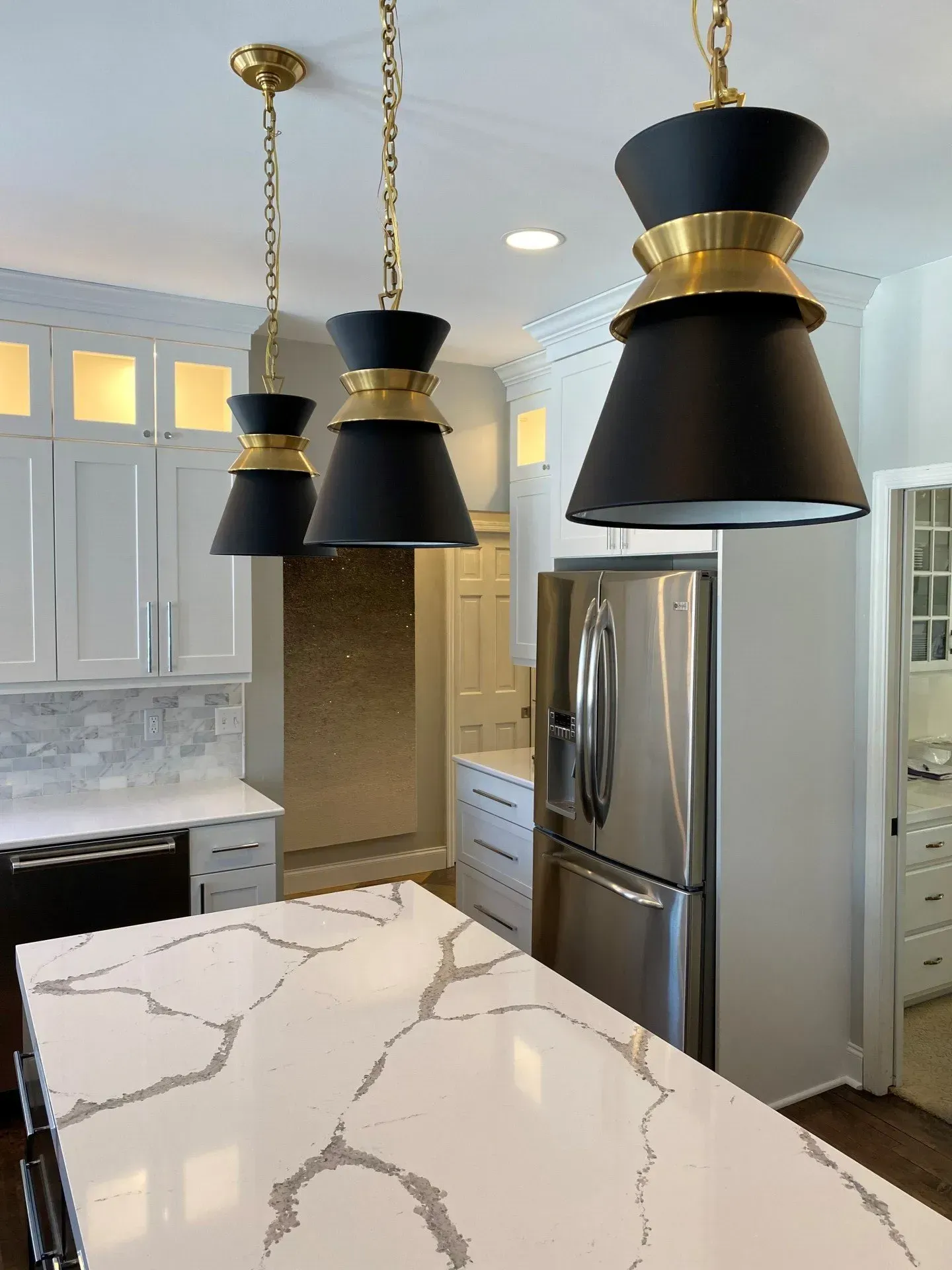 A kitchen with white cabinets , a stainless steel refrigerator , and a large island.