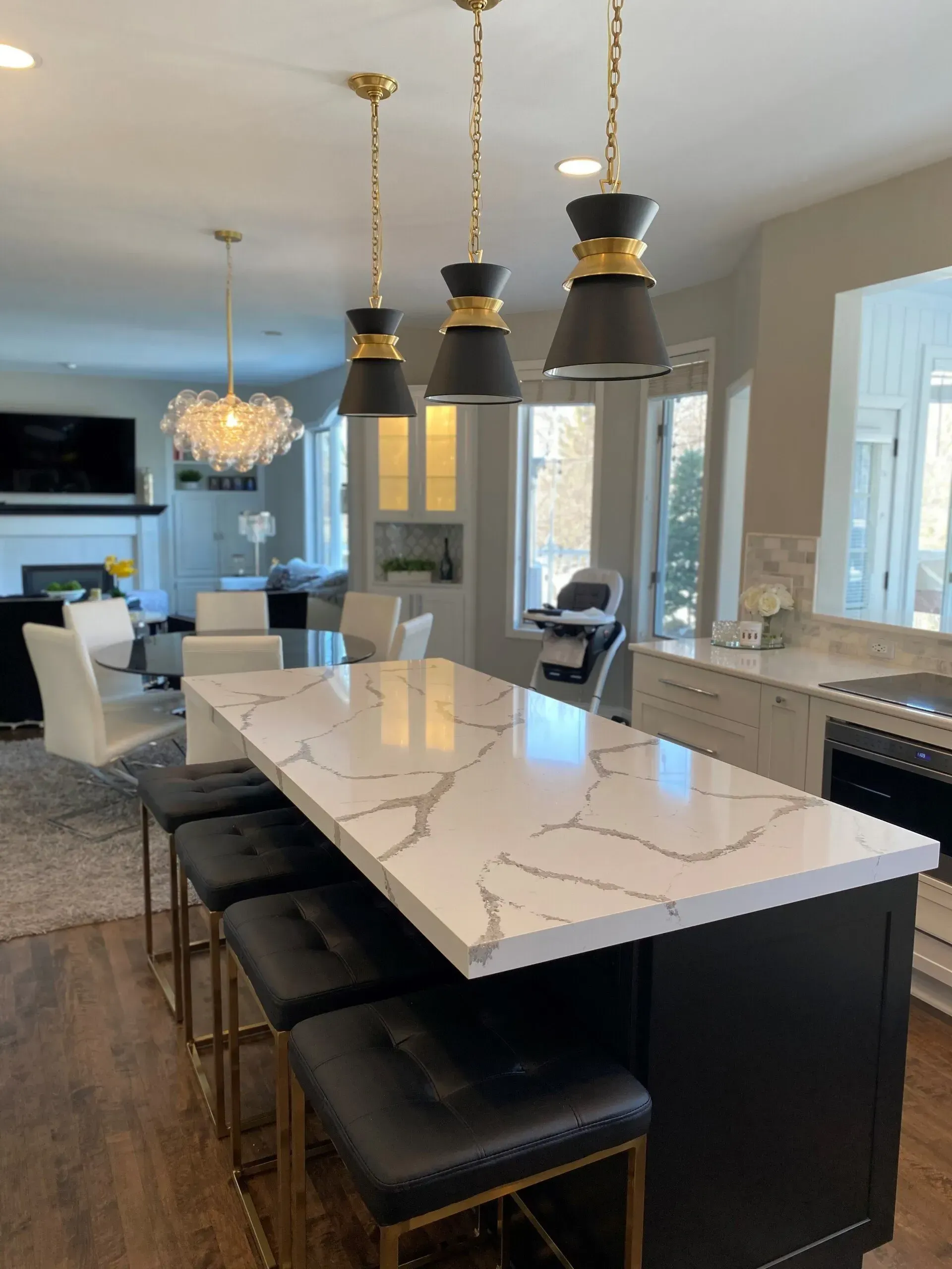 A kitchen with a marble counter top and black stools
