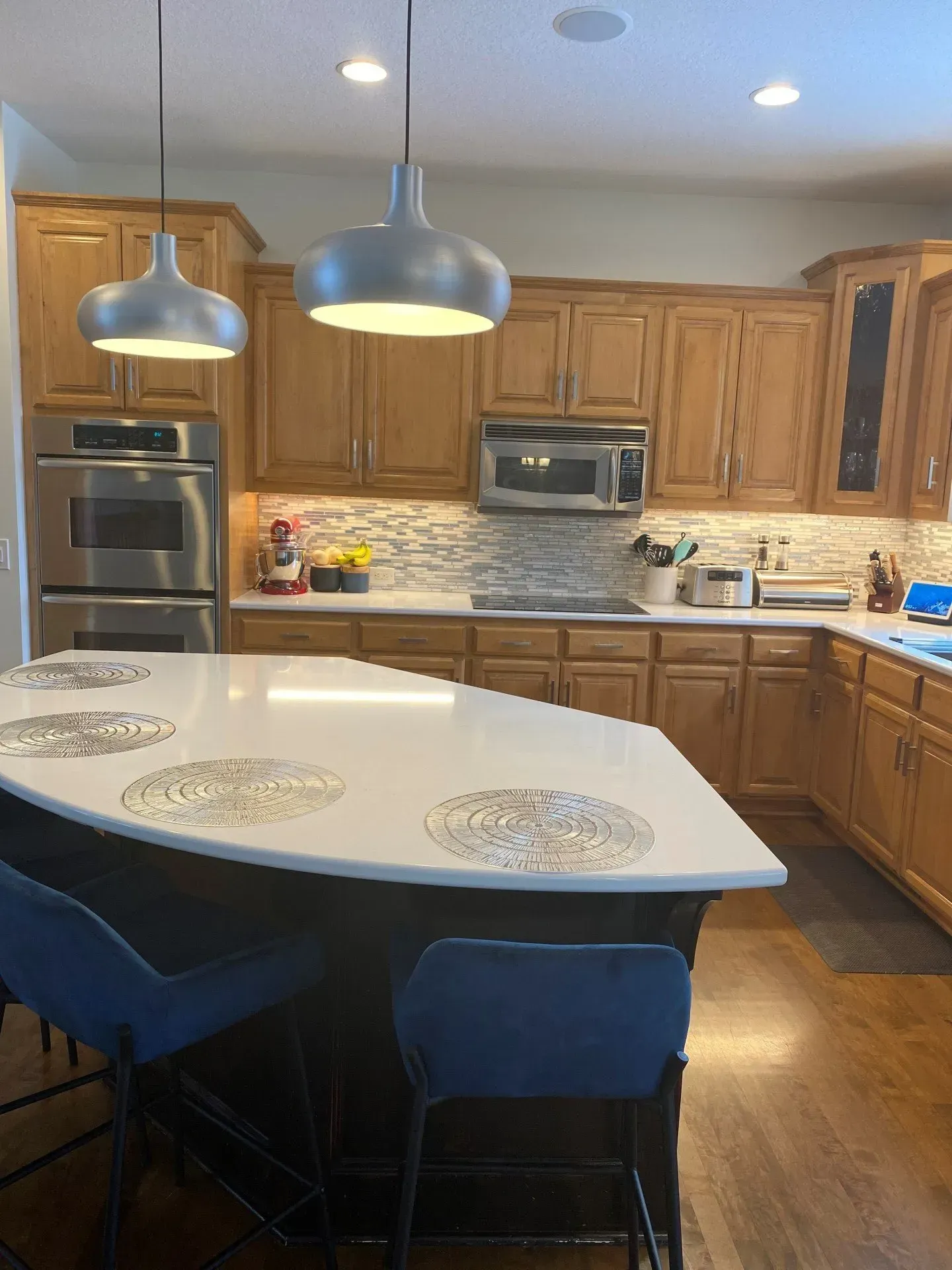 A kitchen with wooden cabinets and stainless steel appliances and a large island.