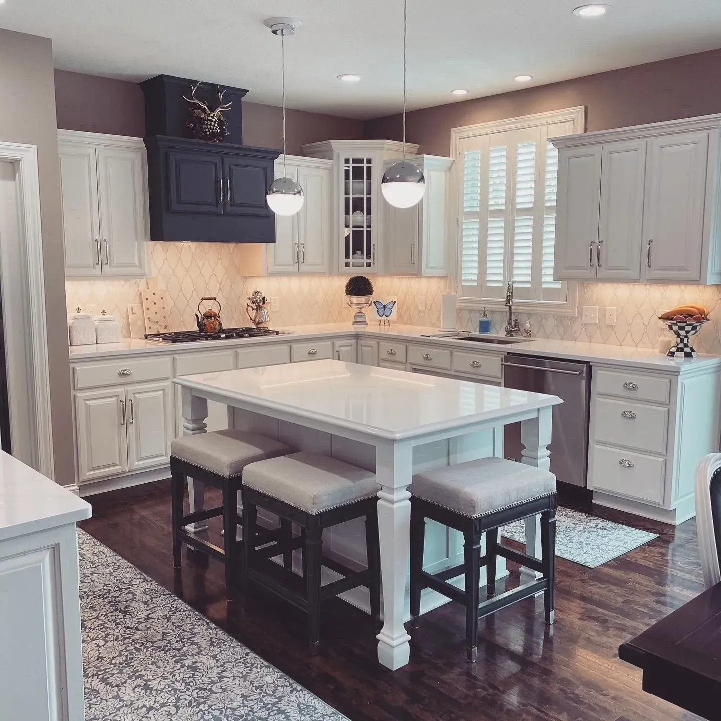 A kitchen with white cabinets and a large island with stools