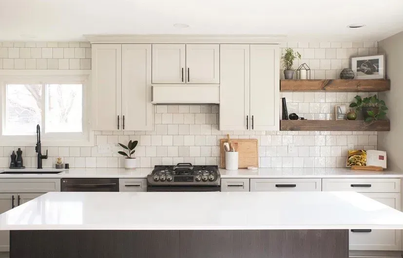 A kitchen with white cabinets , a stove , a sink , and a large island.