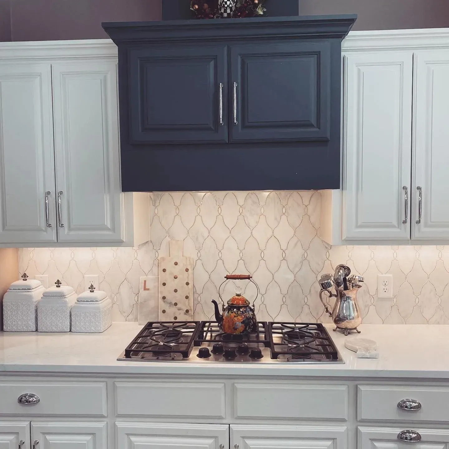 A kitchen with white cabinets and a stove top oven