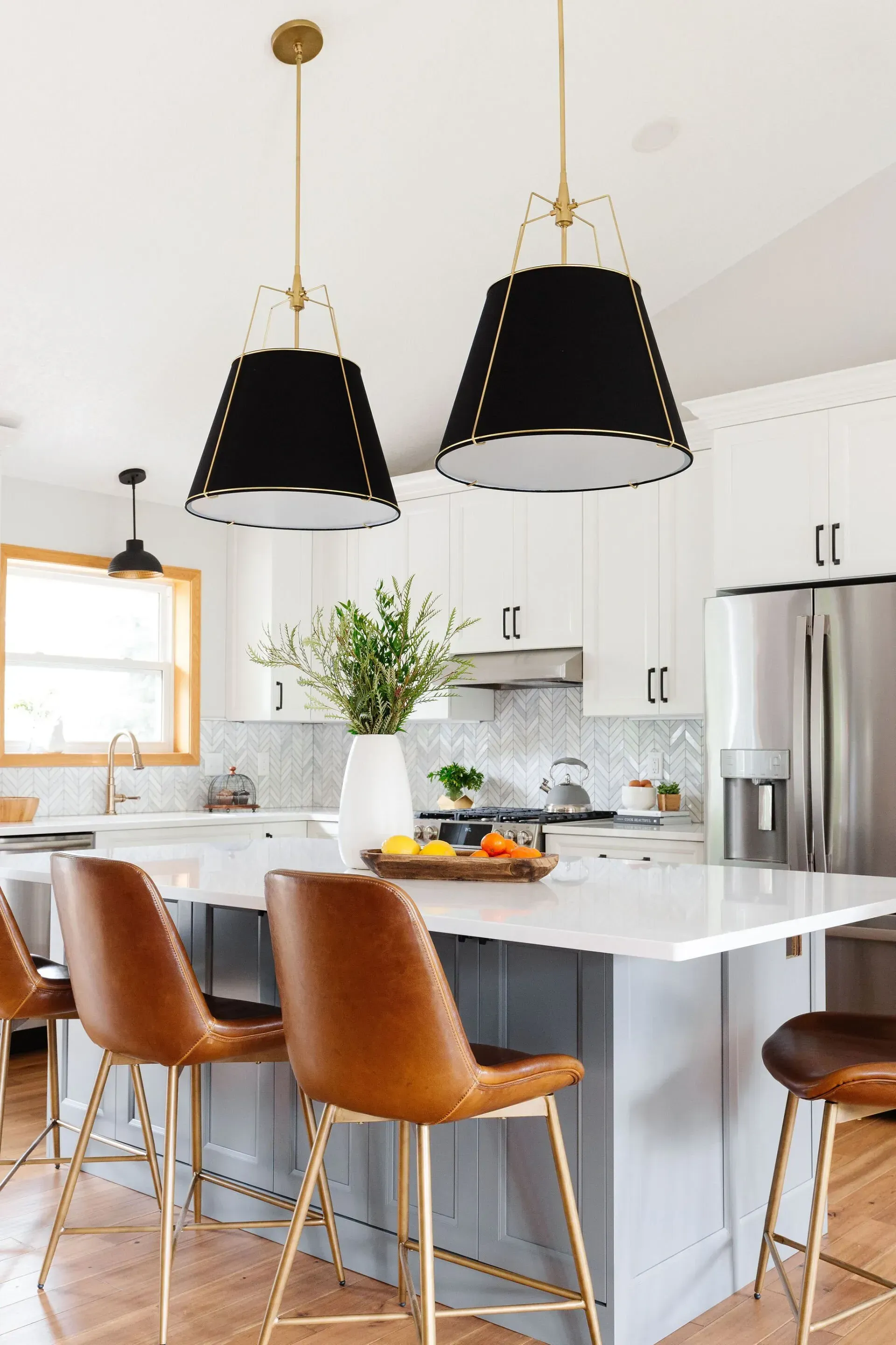 A kitchen with a large island , stools and pendant lights.