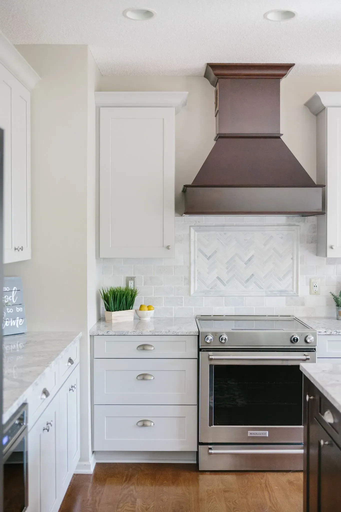 A kitchen with white cabinets , stainless steel appliances , a stove and a hood.