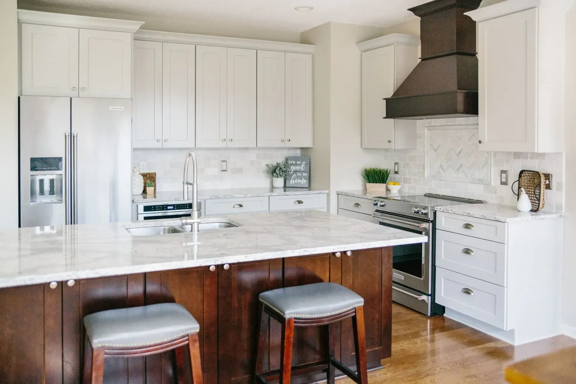 A kitchen with white cabinets , stainless steel appliances , and a large island.