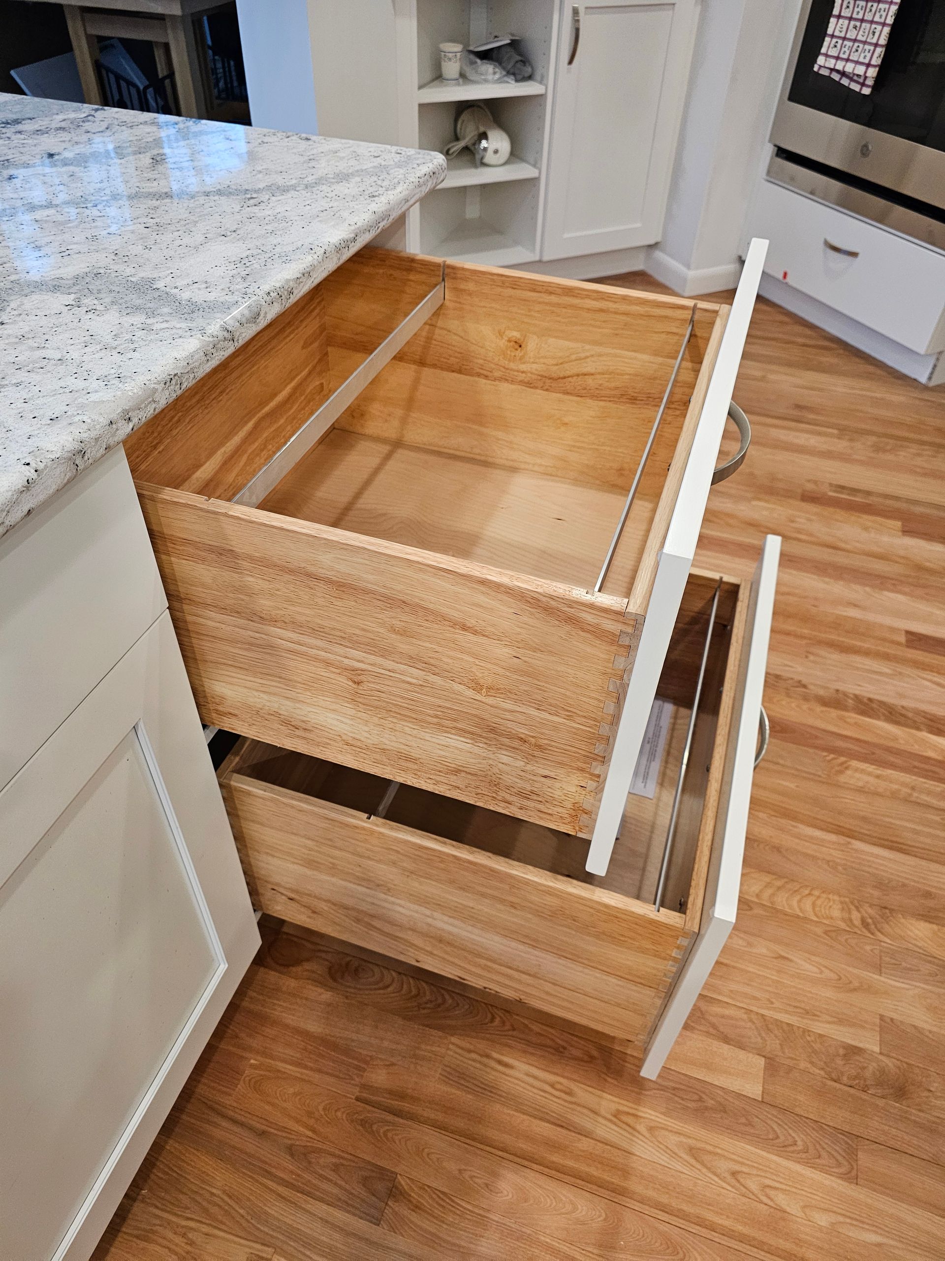 A wooden drawer is open in a kitchen.