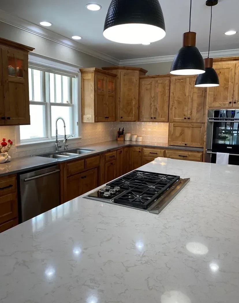 A kitchen with wooden cabinets and a large island with a stove top oven.
