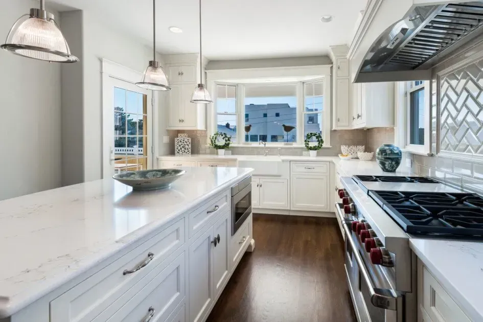 A kitchen with white cabinets , stainless steel appliances and a large island.