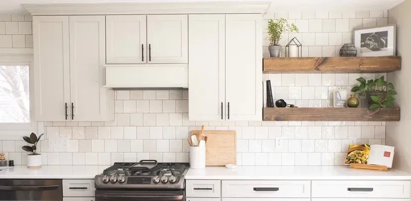 A kitchen with white cabinets , a stove , and a window.
