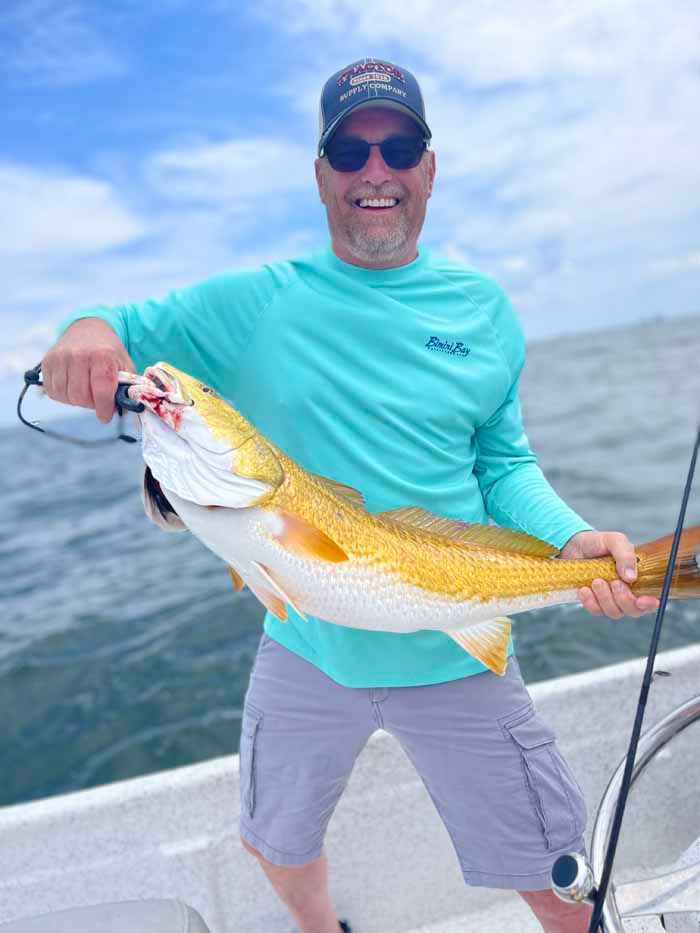 A man is standing on a boat holding a large fish.