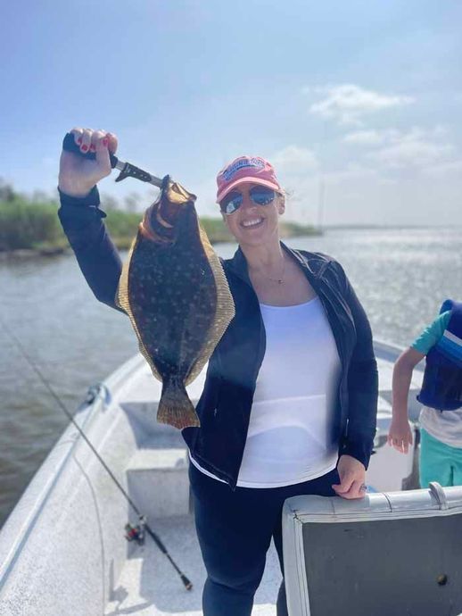 A woman is holding a fish in her hand on a boat.